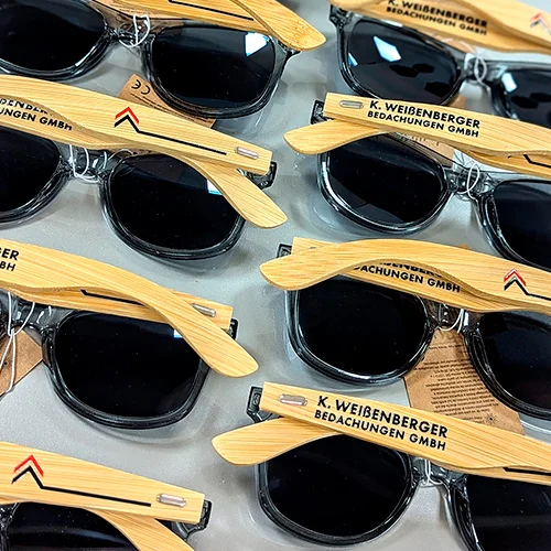 zu sehen sind Sonnenbrillen mit Logo der Firma K. Weißenberger Bedachungen GMBH