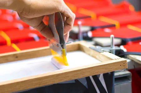 du siehst hier einen Arbeitsschritt beim Siebdruck, bei dem die Farbe mit dem Rakel über die Matrize gezogen wird.