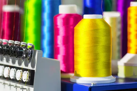 zu sehen sind bunte Garne, die sich auf einer Stickmaschine in unserer Stickerei Schweinfurt befinden