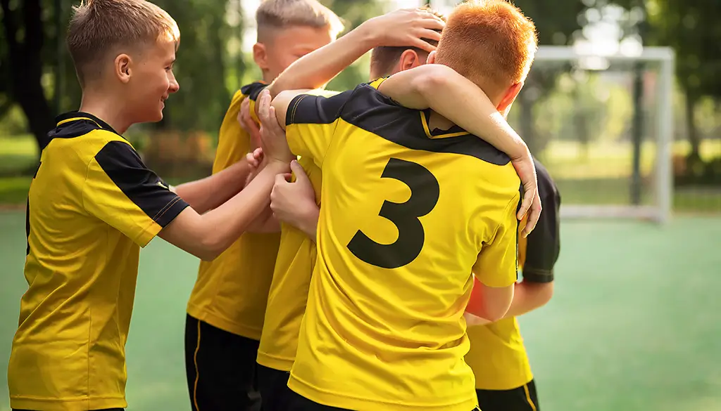 zu sehen sind 4 Kinder, die sich haben ein Fussball Trikot bedrucken lassen, in gelb-schwarz