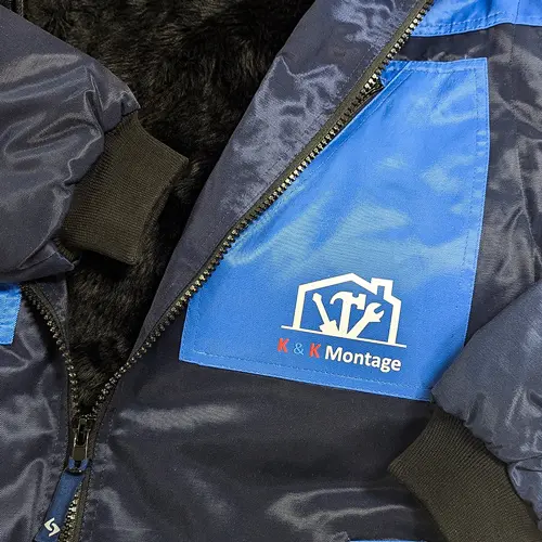 zu sehen ist Arbeitsjacke bedrucken lassen in schwarz/blau mit weißer Aufschrift