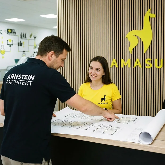 Ein Architekt von Arnstein bespricht den frish gedruckt Bauplan mit einer Mitarbeiterin von Lamasuli.