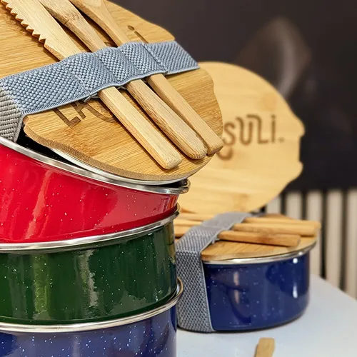 zu sehen sind blaue ,rote und grüne Brotzeitdosen mit Holzdecken und passendem Besteck, veredelt mit dem Schriftzug der Firma Lamasuli