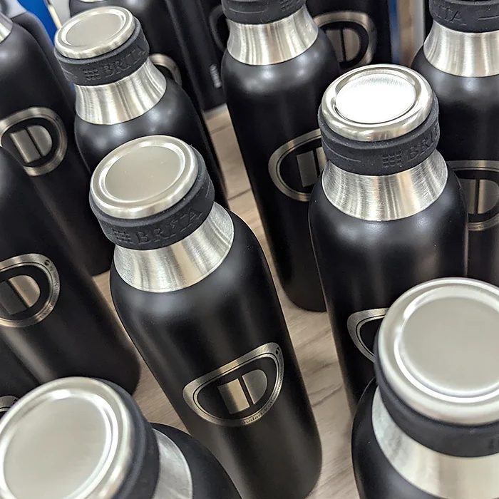 Viele schwarze Thermoflaschen mit dem Logo Daudert Kaffeemaschinen als Gravur.