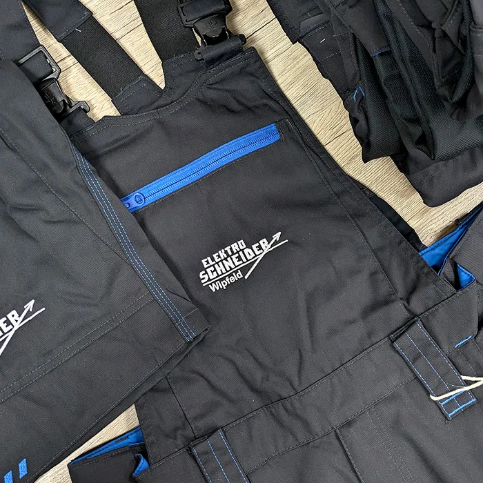 Schwarze Overalls mit aufgesticktem Logo für Elektro Schneider n Schweinfurt.
