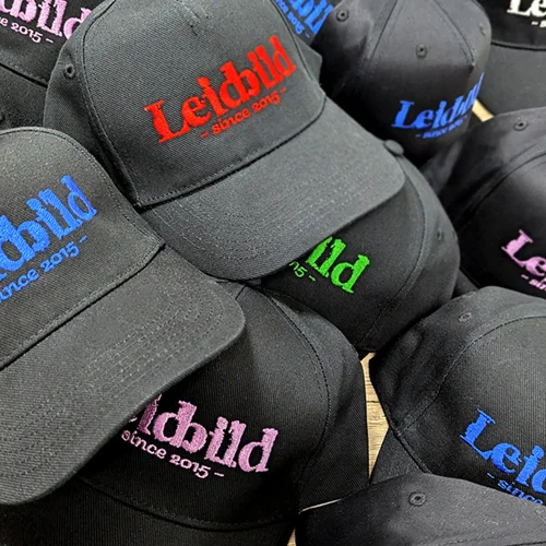 Detailaufnahme einer bestickten schwarzen Cap mit dem Logo Leidbild