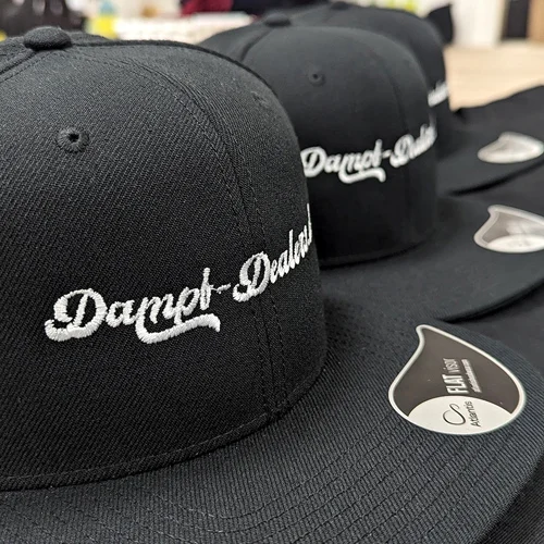 Detailaufnahme einer bestickten schwarzen Cap mit der Aufschrift