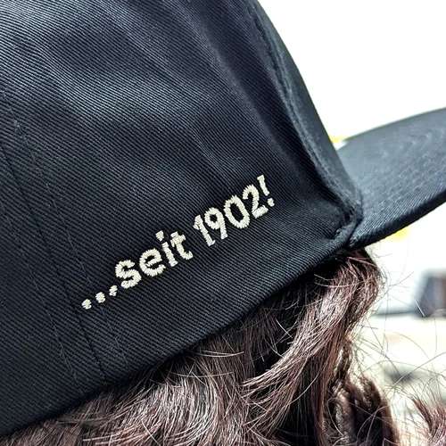 Detailaufnahme einer bestickten schwarzen Cap mit der Aufschrift