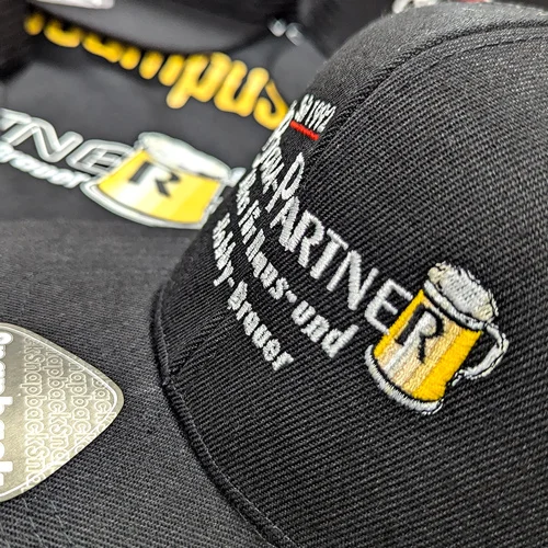 Detailaufnahme einer bestickten schwarzen Cap mit der Aufschrift