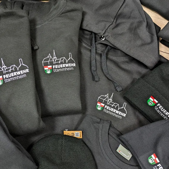Feuerwehr Kleidung für die Feuerwehr Stammheim – Projekt mit Lamasuli Schweinfurt 4 Textilien der Feuerwehr Stammheim, darunter schwarze Mützen und Sweatshirts.