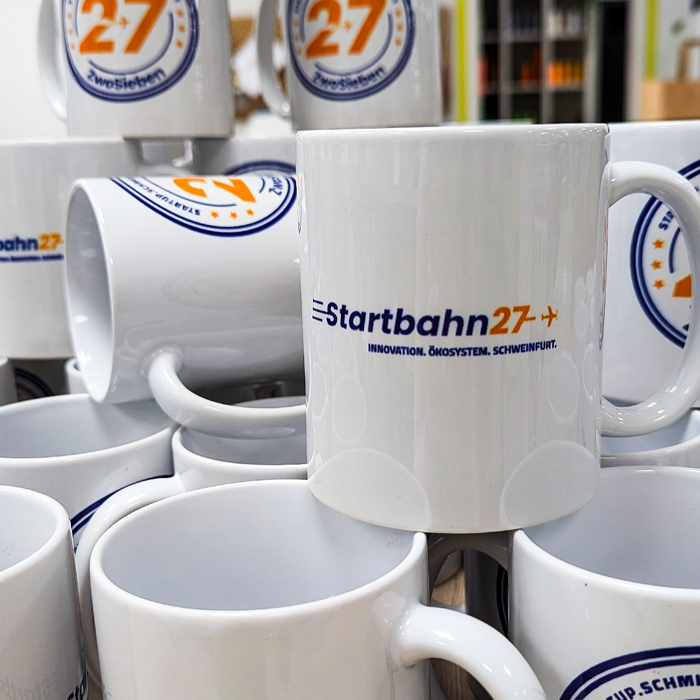 Sichtbarkeit für Start-ups und Gründungsnetzwerke 2 Viele bedruckte Tassen für Startbahn27 in Schweinfurt, umgesetzt von Lamasuli