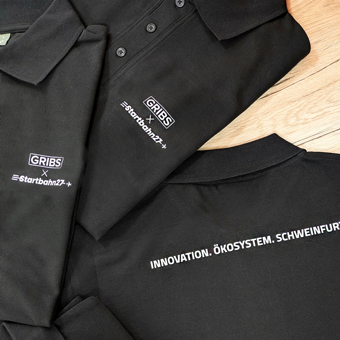 Sichtbarkeit für Start-ups und Gründungsnetzwerke 1 Schwarze bedruckte Polos für GRIBS und Startbahn27 in Schweinfurt, umgesetzt von Lamasuli