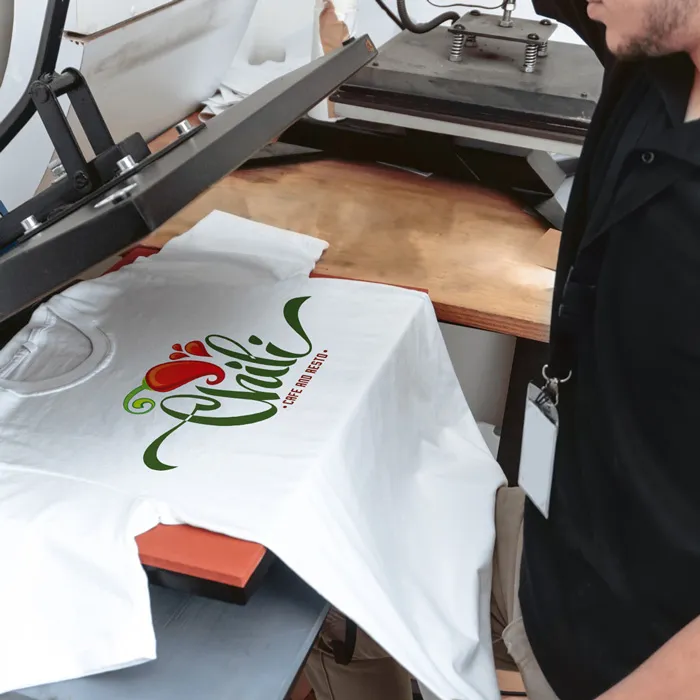 Hoodies bedrucken: Veredelung eines weißen T-Shirts mit dem farbigen Logo von "Chili's Cafe and Resto" mittels einer Transferpresse.