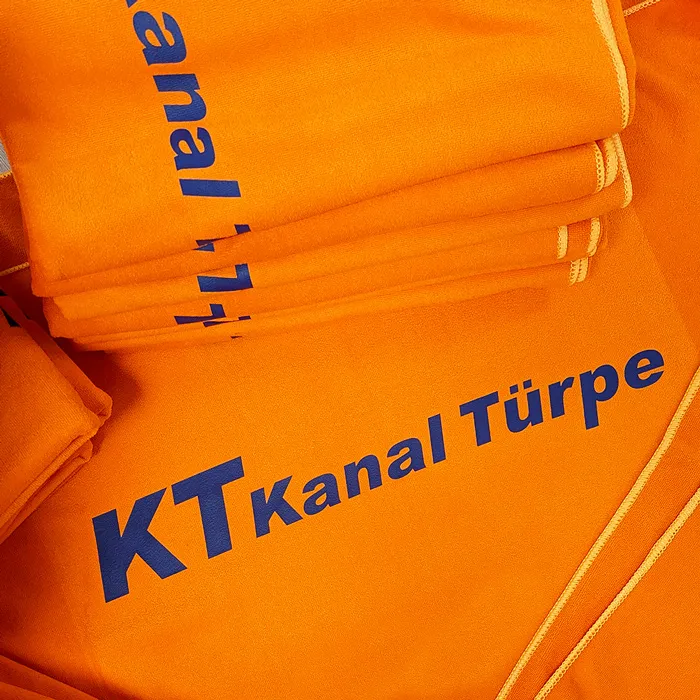 Detailaufnahme von orangefarbenen Handtüchern, gebrandet mit dem Logo von Kanal Türpe.