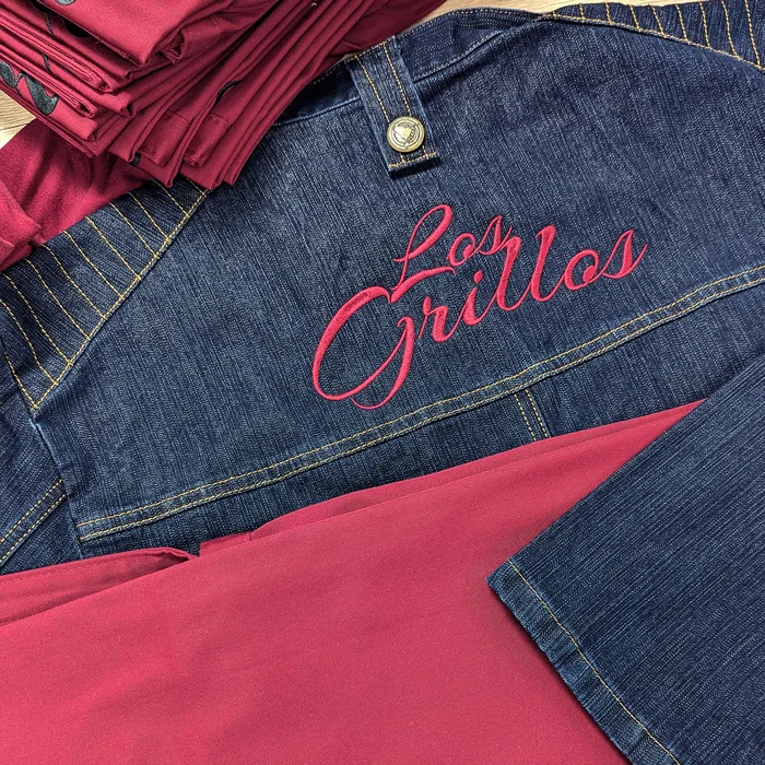 Personalisierte Textilien für D.I.E Kuriere – Projekt mit Lamasuli Schweinfurt 3 Nahaufnahme einer Logostickerei von Los Grillos auf Jeansstoff