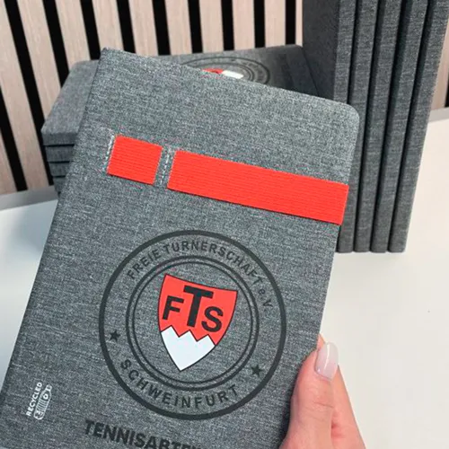 zu sehen ist ein graues Notizbuch aus Filz mit einer Veredelung in rot/schwarz/weiß.