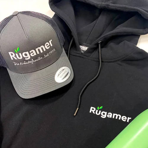 Personalisierte Mitarbeiterausstattung für Georg Rügamer GmbH in Schwebheim mit Lamasuli 6 Eine graue Cap und ein schwarzer Hoodie, alles mit dem Rügamer-Logo von Lamasuli