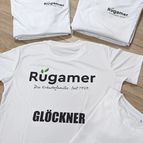 Personalisierte Mitarbeiterausstattung für Georg Rügamer GmbH in Schwebheim mit Lamasuli 5 Nahaufnahme von weißen T-Shirts mit dem bedruckten Logo für Rügamer von Lamasuli