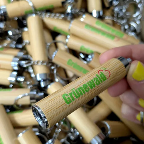 Nahaufnahme mehrerer Schlüsselanhänger aus Bambus mit dem bedruckten Logo "Grünewald" in Grün und Rot.