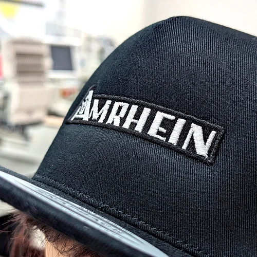Detailaufnahme einer bestickten schwatzen Cap mit dem Logo Amrhein.