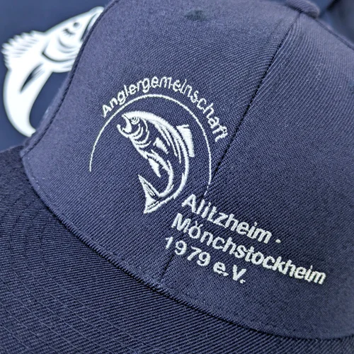 Detailaufnahme einer bestickten blauen Cap mit dem Logo Anglergemeinschaft Alitzheim/Mönchstockheim.