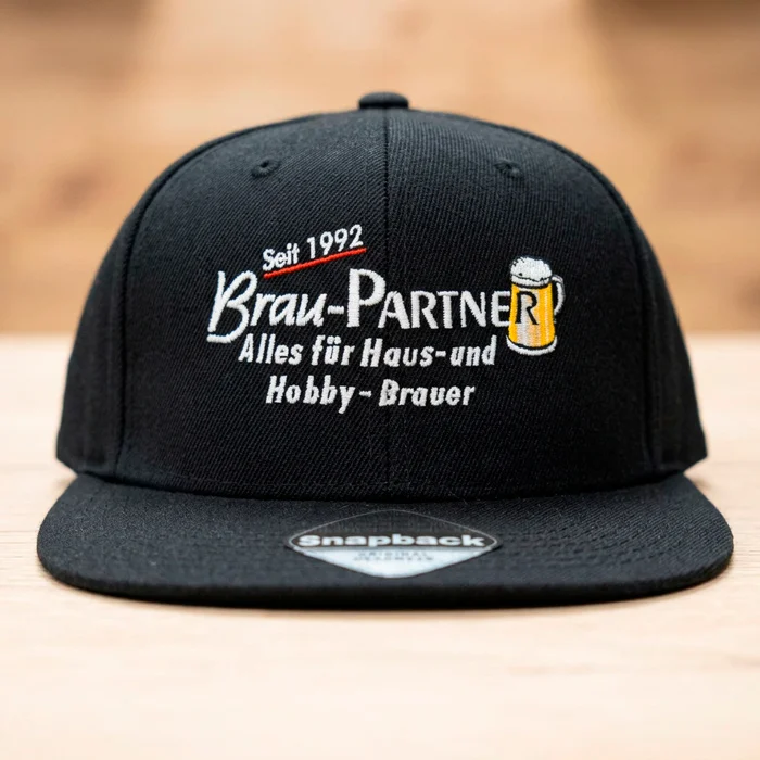 Detailaufnahme einer bestickten schwarzen bestickten Cap als Snapback mit der Aufschrift Brau-Partner seit 1992.