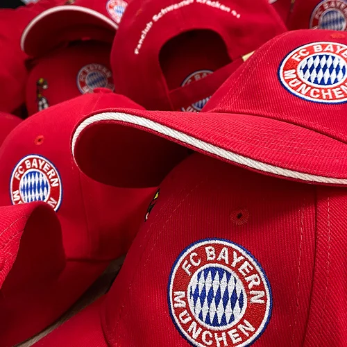 Mehrere rote Caps für Sport mit dem bestickten Logo "FC Bayern München"