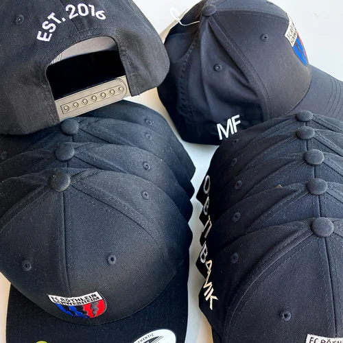 Mehrere schwarze Caps für Sport mit dem bestickten Logo und die Namen