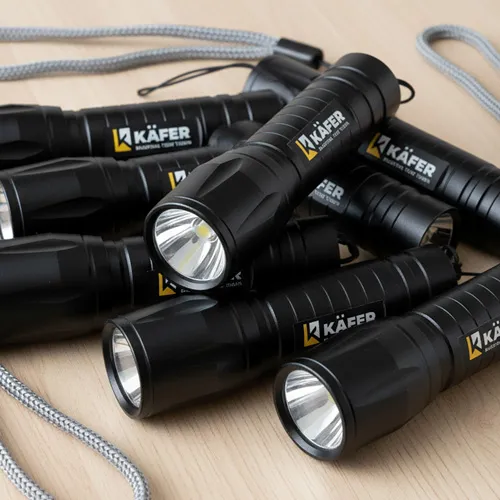Reihe von schwarzen Taschenlampen mit dem gelb-schwarzen KÄFER-Logo auf hellem Untergrund.